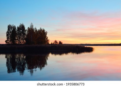 Epic Red And Golden Clouds Above The Forest Lake At Sunrise. Dramatic Cloudscape. Symmetry Reflections On The Water, Natural Mirror. Idyllic Rural Scene. Gauja National Park, Sigulda, Latvia