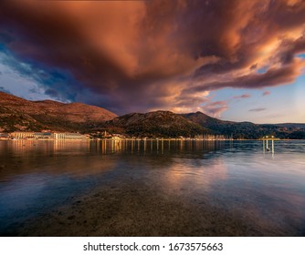Epic scene of cloudscape on beachfront, town on coastline reflects on water surface