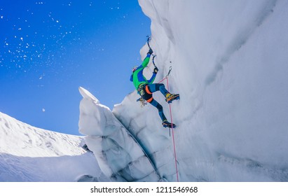 Epic shot of an ice climber climbing on a wall of ice. Mountaineer and climber on an adventure extreme ascent with ice axe and crampons. Alpine extreme climbing on a serac or creavasse.