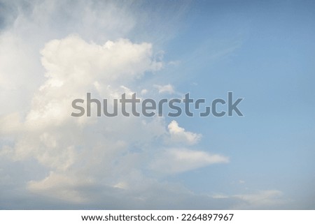 Epic storm cloudscape. White ornamental sunset cumulus clouds. Soft golden sunlight. Clear blue sky. Natural pattern, texture, background, wallpaper, graphic resources, design, copy space