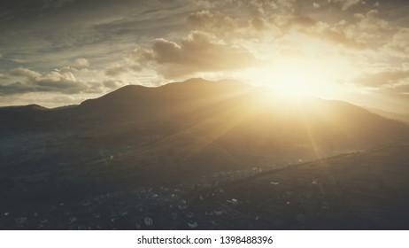 Epic Sunrise Sun Flare Mountain Village Aerial View. Morning Highland Suburban Town Scenery Hill Countryside Overview. Clouds Fast Flow In Sky. Copter Rise Up. Timelapse Drone Flight