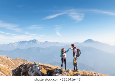 Epic view of mountain ridge and range in the haze under the sun and victory gesture high five hands of hiker couple. Motivation, support, love, and success concepts. - Powered by Shutterstock