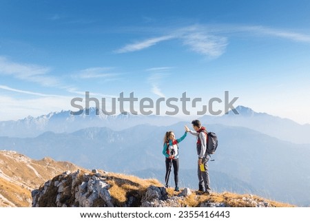 Epic view of mountain ridge and range in the haze under the sun and victory gesture high five hands of hiker couple. Motivation, support, love, and success concepts.