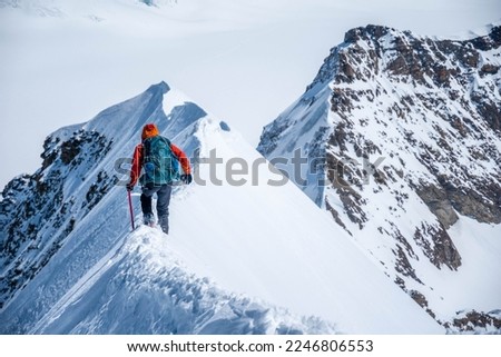 Epic view on descending alpinist on a steep narrow snow ridge, extreme climbing mountaineer, Monch, Bernese Alps, Swiss