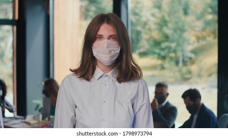 Epidemic Protection. Portrait Of Young Attractive 20s Business Woman Putting Mask On Face In Modern Office Slow Motion.