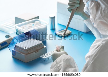 Epidemiologist in protective suit, mask and glasses works with patient swabs to detect specific region of 2019-nCoV virus causing Covid-19 viral pneumonia. SARS-COV-2 pcr diagnostics kit concept.