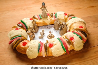 Epiphany Cake, kings cake, or Rosca de reyes with manger on wooden table