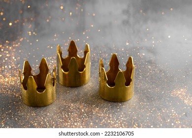 Día de la Epifanía o concepto de Dia de Reyes Magos. Tres coronas doradas sobre fondo negro con partículas doradas.