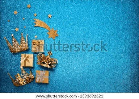 Epiphany Day or Dia de Reyes Magos concept. Three gold crowns and gifts on blue sparkling background