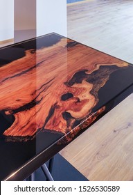 Epoxy resin table made of olive wood on a black  background with steel bars as table legs