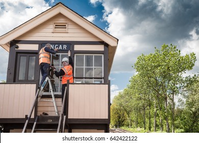 EPPING ONGAR, UK - MAY  16,  2013:  Men In Work Gear Fix A Sign On A Signal Box On The Epping Ongar Railway