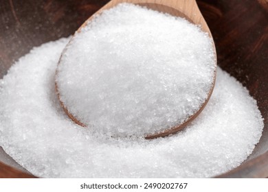 Epsom salt (Magnesium sulfate) crystals in wooden spoon close up. Relaxing spa ingredient