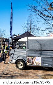 Epsom Surrey London UK, March 17 2022, Workman With Yellow Vest Using Mobile Phone Walking Past Closed Pop Up Food Van