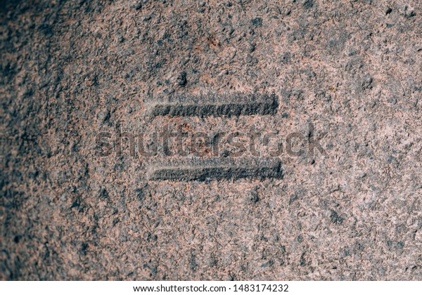 An equal sign carved on the stone. Mathematical\
sign on granite. Stone\
engraving