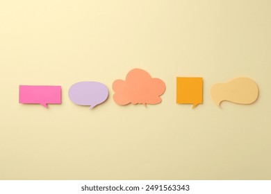 Equality concept. Different paper speech bubbles on beige background, flat lay