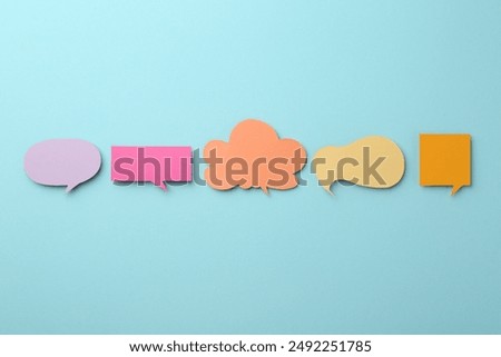 Equality concept. Different paper speech bubbles on light blue background, flat lay