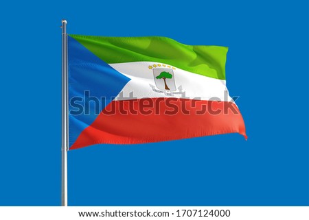 Equatorial Guinea national flag waving in the wind on a deep blue sky. High quality fabric. International relations concept.