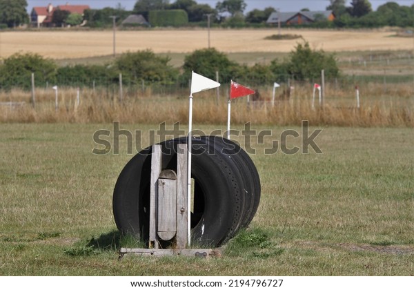 Equestrian cross country\
tyre jump with flags either side at a schooling venue where horses\
go to practice. 