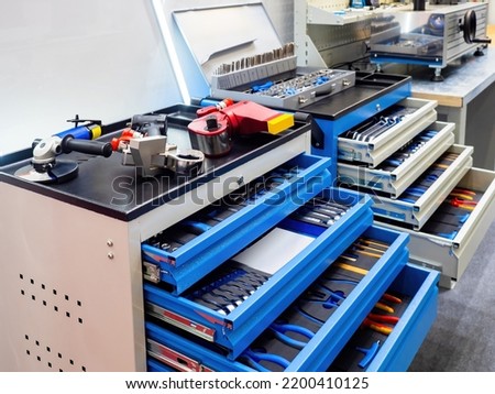 Equipment for car mechanic. Metal carts with tools. Trolleys with tools in workshop. Workplace of mechanic. Equipment for locksmith work. Metal cabinets with drawers. Sale of equipment for mechanic.