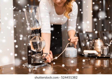 Equipment, Coffee Shop, People And Technology Concept - Close Up Of Woman With Butane Gas Burner Heating Water In Siphon Coffeemaker At Cafe Bar Or Restaurant Kitchen Over Snow