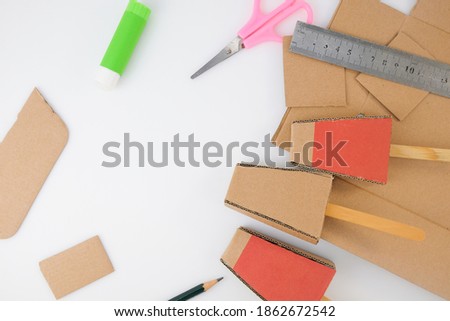 Equipment for making cardboard ice cream craft on white background: scissors, pencil, glue, rulers, old cardboard. 