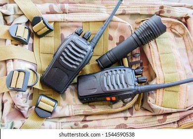 Equipment for trekking. Set of traveler or tourist or soldier. Radio for communication, flashlight on the background of a military backpack camouflage. - Powered by Shutterstock