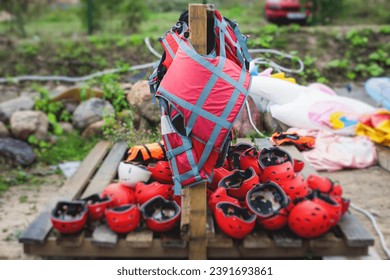 Equipment for water sports: bunch of wetsuits, paddles, red helmets and life jackets, preparing for rafting, kayaking, canoeying and stand up paddle, preparing to extreme water sports and tourism - Powered by Shutterstock