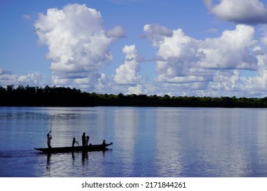 Er Village, Asmat Regency, June 22, 2022. A Family Is Rowing A Wooden Boat In The Middle Of The Shady Pomats River Against A Backdrop Of Blue Clouds This Summer                   