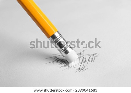 Erasing scribbles with graphite pencil on white background, closeup