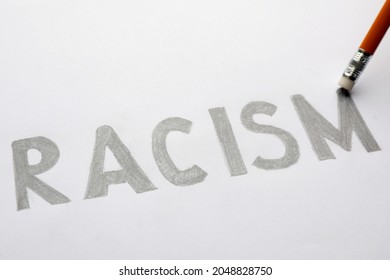 Erasing Word Racism Written On Paper Sheet With Pencil, Closeup