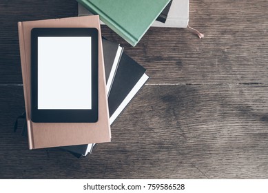 e-reader on stack of books on rustic wooden desk