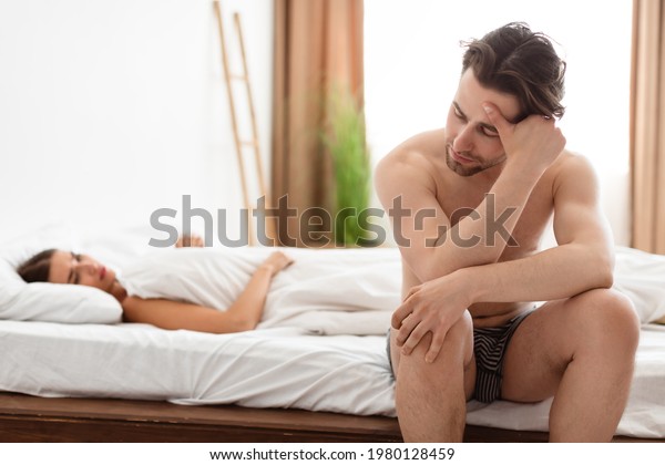 Erectile Dysfunction. Unhappy Man Having Erection\
Problems While His Girlfriend Lying In Bed In Bedroom At Home.\
Sexual Failure And Stress. Impotence, Male Health Issue. Selective\
Focus