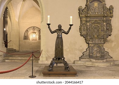 ERFURT, GERMANY - DECEMBER 12, 2018: Wolfram, a bronze candlestick (c. 1160) in Erfurt Cathedral. A stucco altar of The Enthroned Madonna with Saints (c. 1160) is visible in the background left.