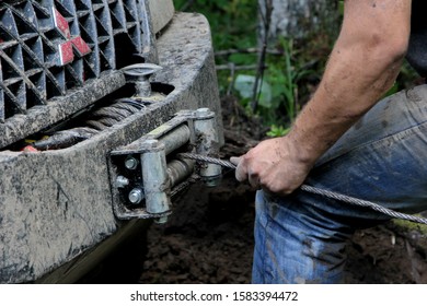 
Ergli, Latvia - July 16, 2016: Latvian Car Club Off-road Race In The Forest For Off-road Cars And Jeep. A Man With A Rope And A Winch In Front Of The Car