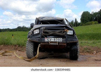 
Ergli, Latvia - July 16, 2016: Latvian Car Club Off-road Race In The Forest For Off-road Cars And Jeep. A Man With A Rope And A Winch In Front Of The Car