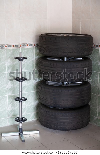 Ergonomics in the garage. Car wheel set\
vertically mounted in the corner of the garage for long-term\
storage. There is a vertical rack\
nearby\
\
