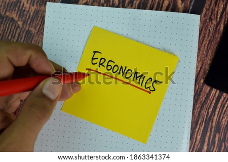 Ergonomics write on sticky notes isolated on Wooden Table.