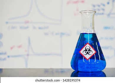 Erlenmeyer flask with Deep Blue liquid and chemical hazard warning symbols labels (biohazard sign) on whiteboard with chemical learning background.