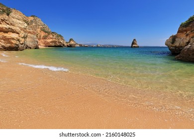 Eroded cliffs and sea stacks of sandstone-limestone frame the south and north sections of Praia do Camilo Beach-tourist motorboats and sea kayaks passing by-beachgoers at swim. Lagos-Algarve-Portugal. - Shutterstock ID 2160148025