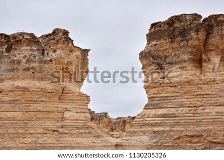 Eroded limestone rock faces at Castle Rock Badlands with pillar formations showing the layers of the strata against a grey cloudy sky