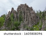 Eroded rock formations and trees stand tall against a storm cloudy spring sky in Custer State Park, South Dakota.