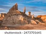 Eroded rock strata leave peculiar geological formations at Bisti - De-Na-Zin wilderness during sunset against a blue sky in New Mexico, USA