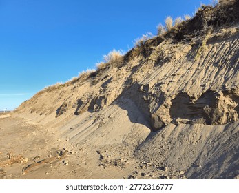 Eroding sandy beach cliff showing impact of climate change on coastline