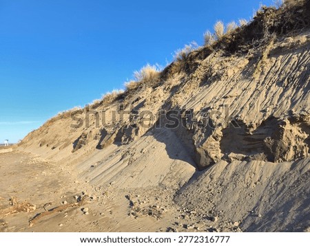 Eroding sandy beach cliff showing impact of climate change on coastline