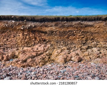 Eroding soil, subsoil and bedrock at a pebble beach near Sand Wick and Hillswick in Northmavine, Shetland, UK. Taken on a sunny day with a blue sky in the background. - Shutterstock ID 2181280857