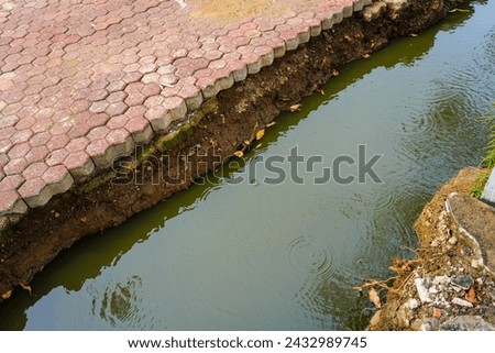 The erosion and reshaping of brick blocks along the edge of a residential water channel