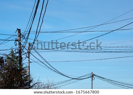 Erratically laid electrical wires on metal supports with a blue sky background