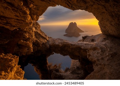 Es Vedra islet at sunset viewed through the rock holes of a cave in Ibiza, Sant Josep de Sa Talaia, Balearic Islands, Spain - Powered by Shutterstock