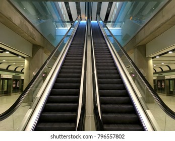 Escalator at an airport with no people. Two escalators in symmetry going up and down inside an airport going from one floor to the other. Modern and sleek interior an airport. Steal, metal, shinny. - Powered by Shutterstock