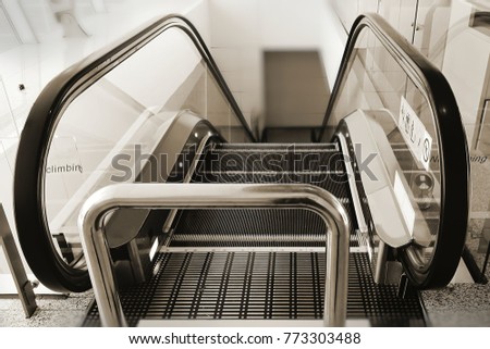 Escalator with lines outlining every steps for marking boundary of safety area; installed bollard on top to prevent and stop baggage trolleys. Selectiv focusin black and white colors